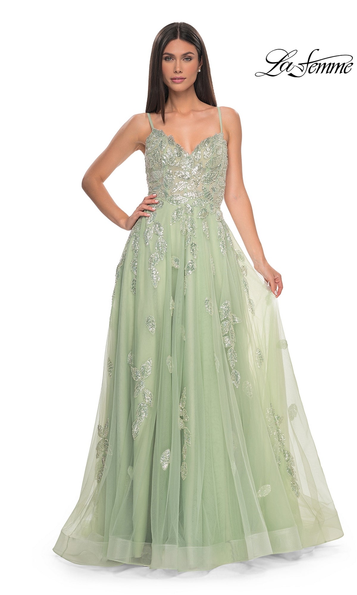 A woman wears the La Femme Sequin-Embroidered Long Prom Dress 32090, a light green A-line gown with thin straps and floral sequin embroidery, standing against a white background. The La Femme logo appears in the top right corner.